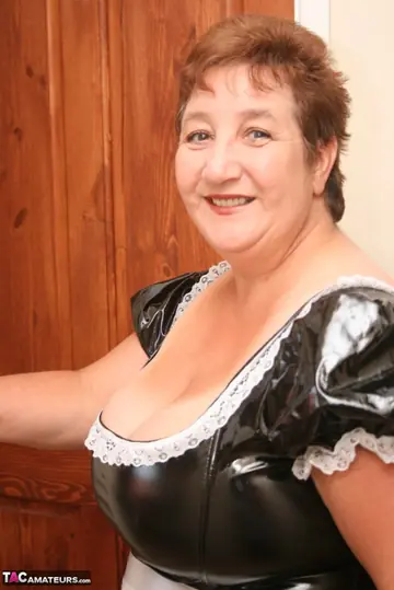 Kinky Carol – Mature Brunette Unbuttons Her Latex Maid Outfit to Show Her Big Tits