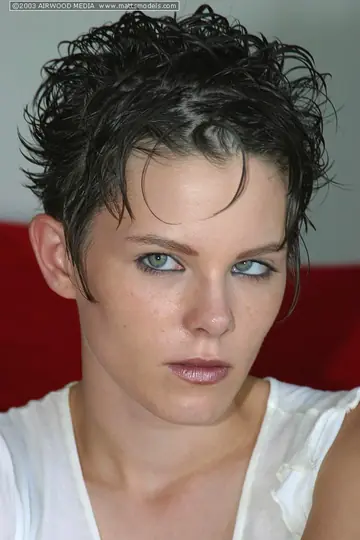 Busty Short-Haired Woman Strips Out of Her Jeans on the Sofa