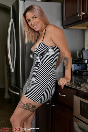 RoXXXie Blakhart – Busty MILF Strips Out of Her Skirt in the Kitchen and Fingers Her Shaved Pussy