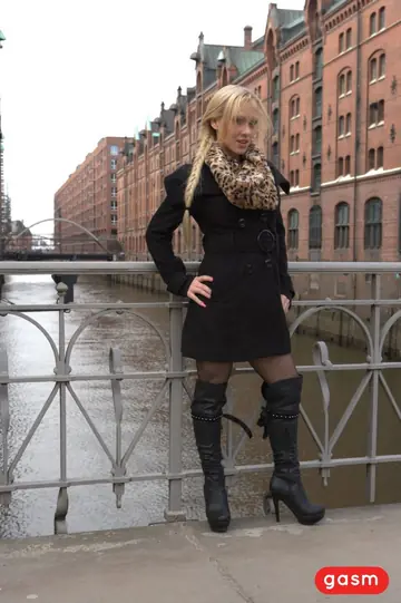 German Blonde Models a Dress, Stockings and Boots Outdoors