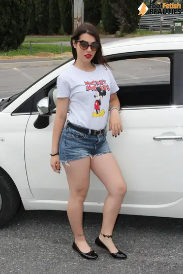 Outdoors, a Brunette in Shorts and Glasses Shows Her Feet
