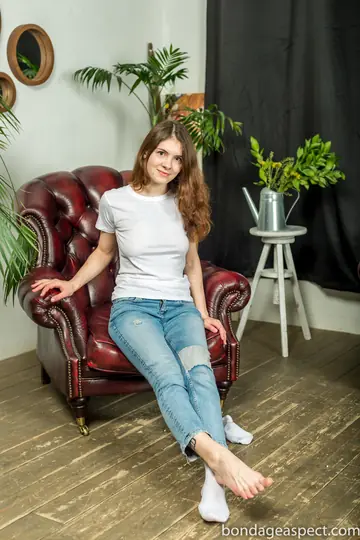 Tattooed Woman in Faded Jeans Spreads Her Legs to Show Her Feet