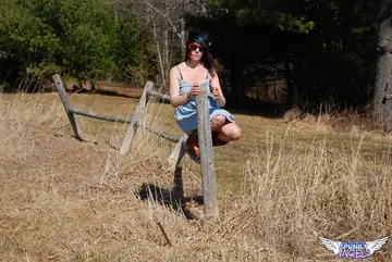 Thick Woman in Glasses and Boots Hikes Her Dress on a Farm