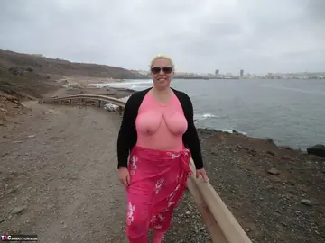 Mature Blonde in Glasses Frees Her Big Tits from Bodystocking at the Beach