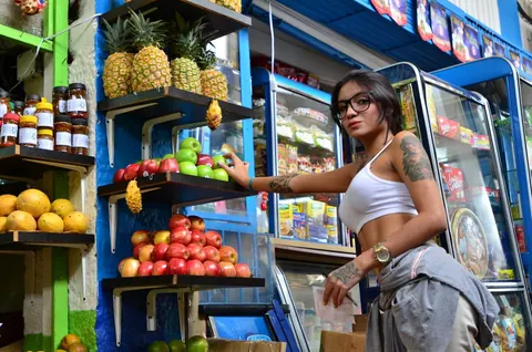 Marly Romero: Tattooed Latina in Glasses Eats a Banana Outdoors – photo 2 of 15